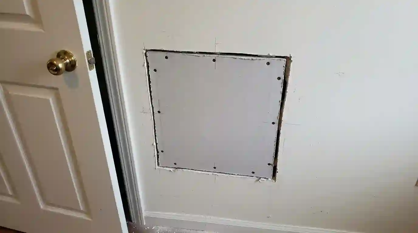 Moisture meter on a swollen baseboard next to a failed shower pan